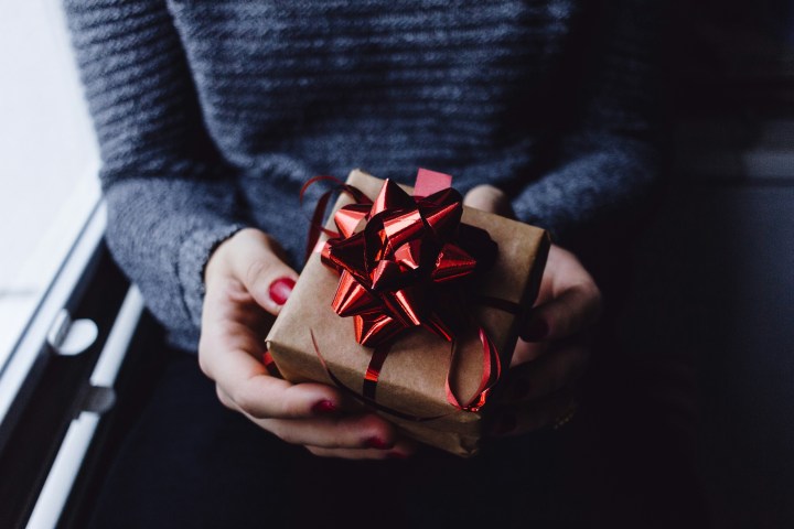 Person holding a small gift box with a red bow.