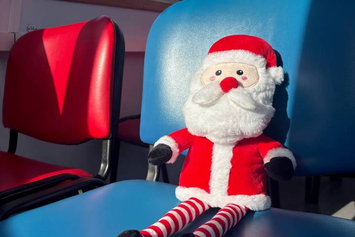 Santa doll on blue chair in sunlit room.